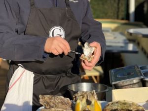 Photo d'un écailler qui ouvre une huitre